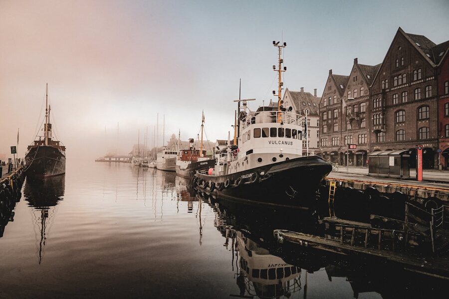 Foggy Bergen harbour at first light with boats and old buildings
