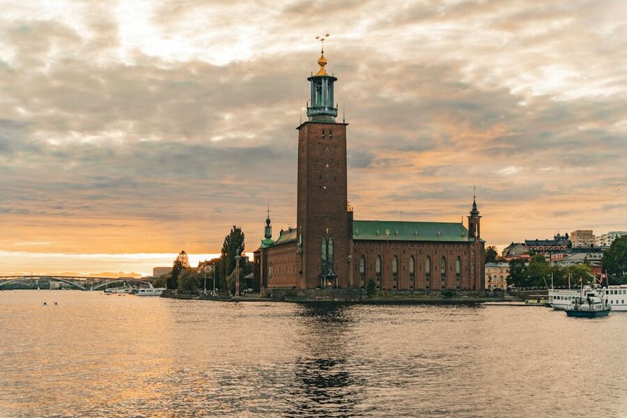 Stockholm City Hall, Stadshuset, with its distinctive square brick tower lit at sunset over Lake Mälaren