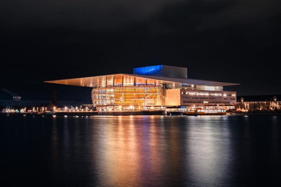 The Copenhagen Opera House illuminated at night across the inner harbour