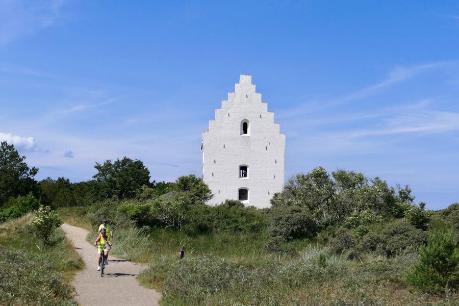 A cyclist on the path approaching Den Tilsandede Kirke