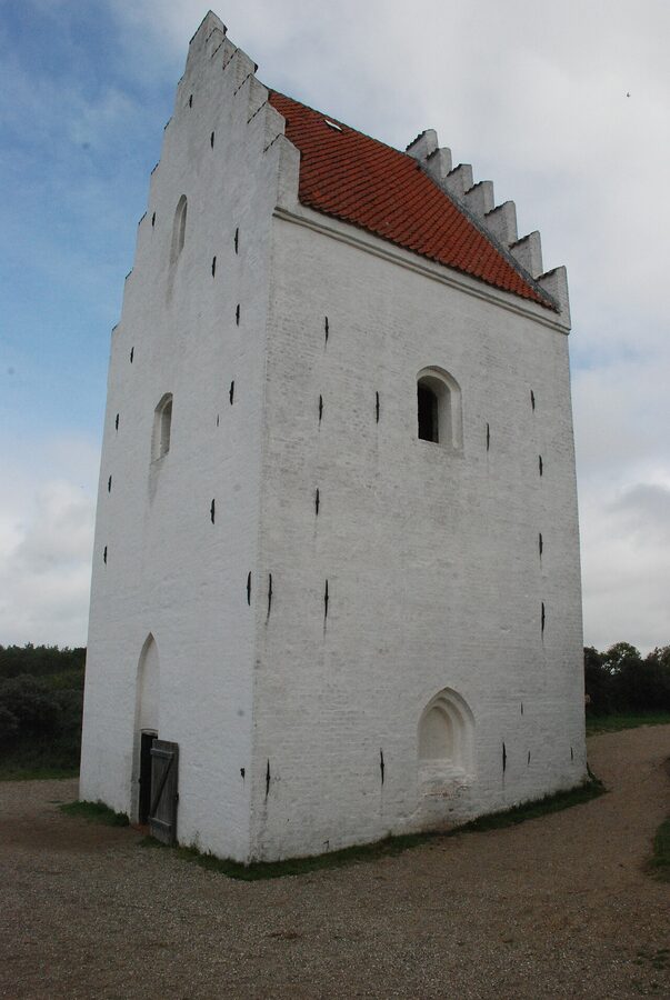The whitewashed tower of Den Tilsandede Kirke standing alone in the dunes