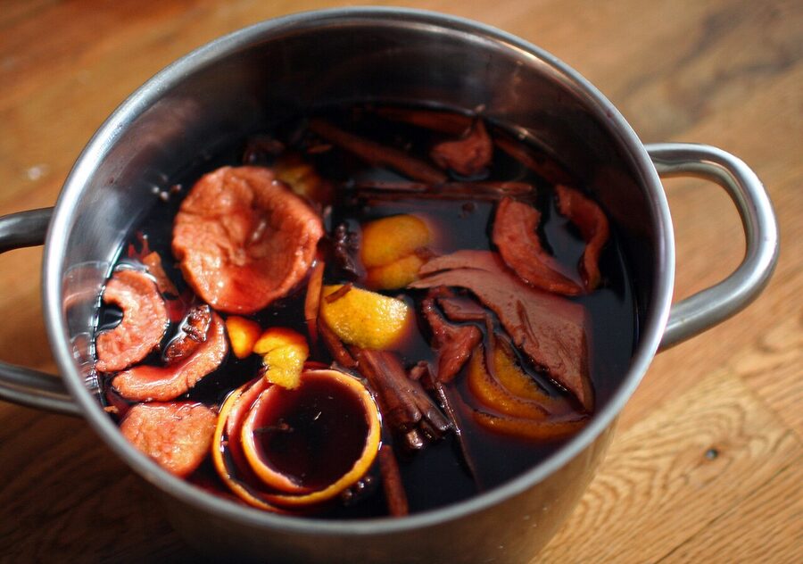 Glögg simmering in a metal pot with raisins and almonds