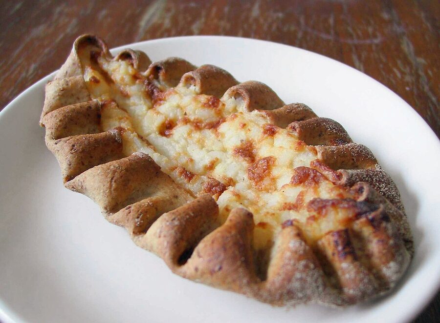 Three classic Karelian pies on a wooden cutting board
