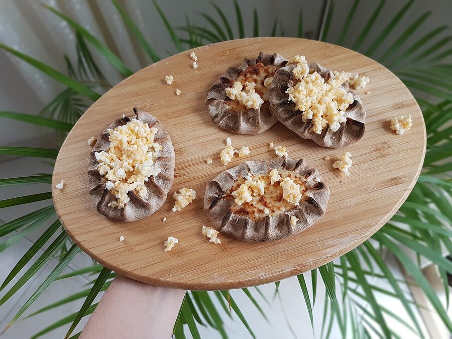 A Karelian pie (karjalanpiirakka) topped with egg butter on a wooden surface, the canonical Finnish breakfast