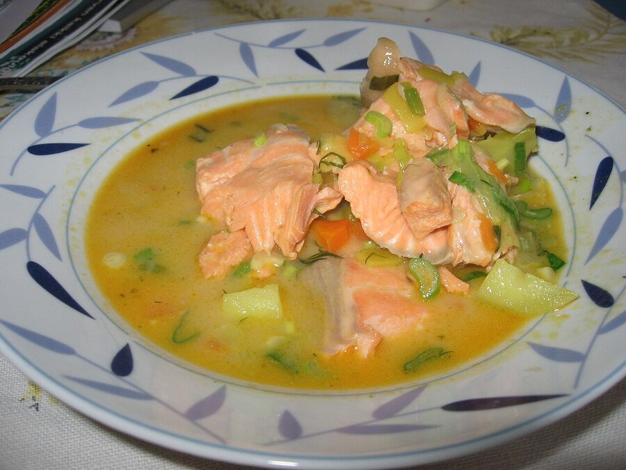 A close-up bowl of lohikeitto with chunks of salmon, potato and leek