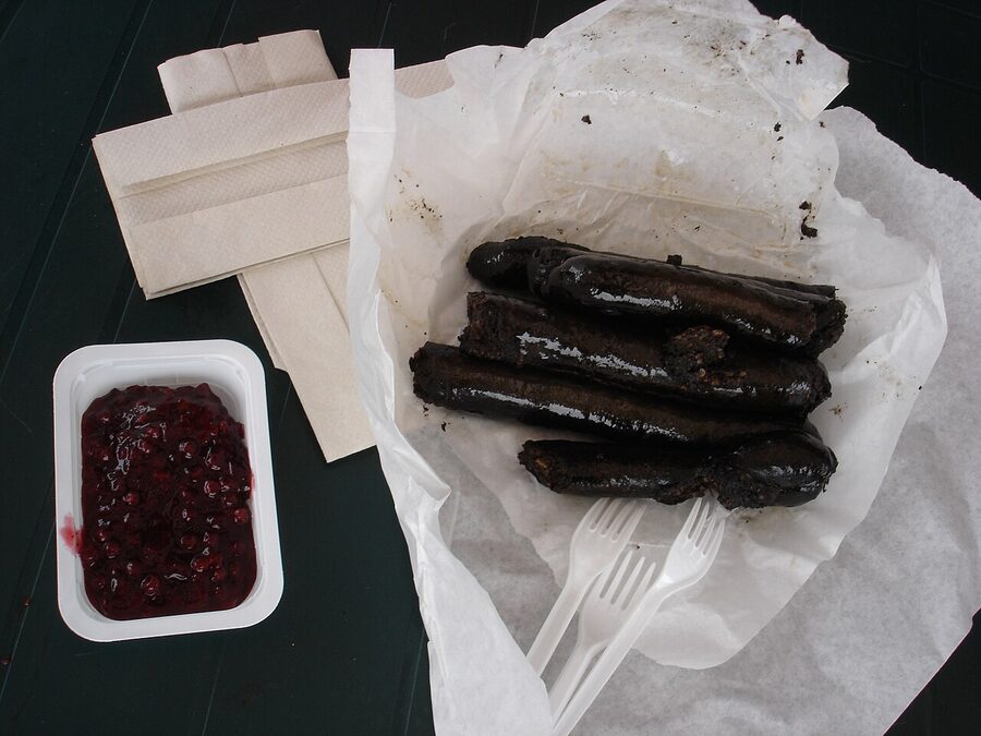 Mustamakkara on a paper tray at the Tampere market hall, served with lingonberry jam
