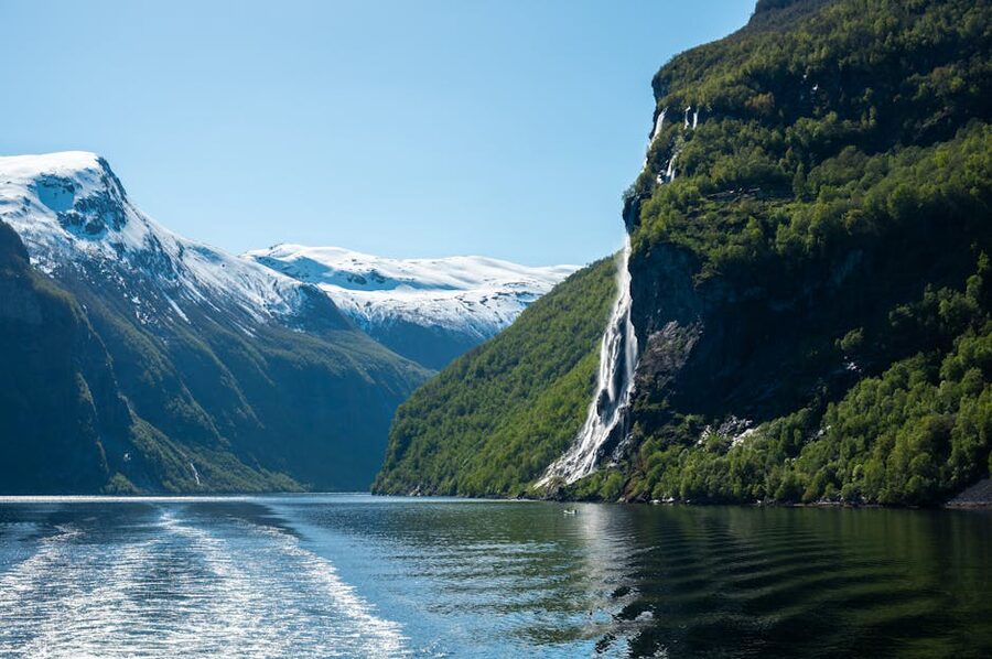 Small boat under snow-streaked cliffs in Geirangerfjord