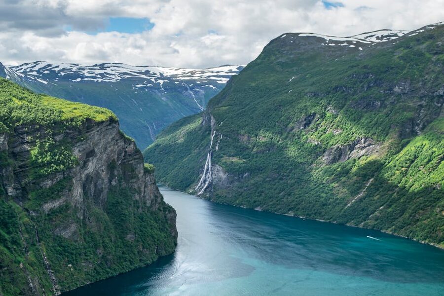 Tall cliff in Geirangerfjord with thin waterfall threading down to the water