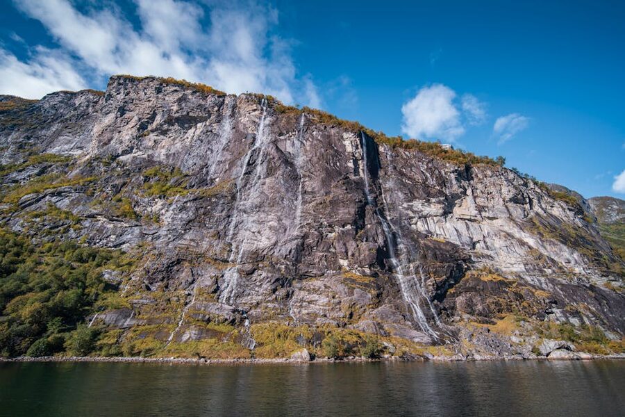 Waterfall cascading down rocky cliff inside Geirangerfjord