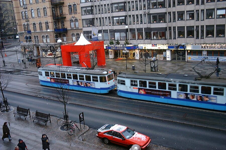 A blue and white Gothenburg tram on a city street