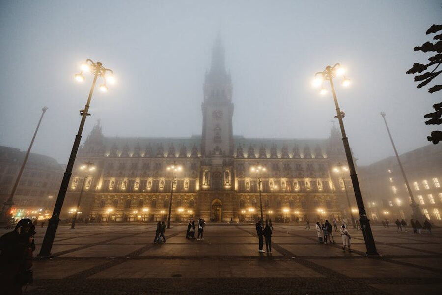 The Rathaus illuminated at night with people in the square