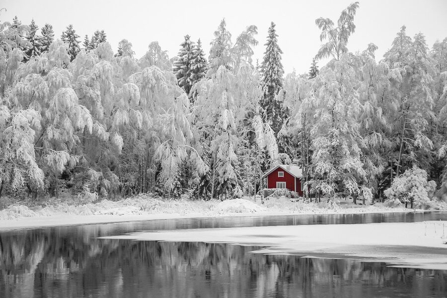A small Finnish lakeside sauna cottage with snow on the roof