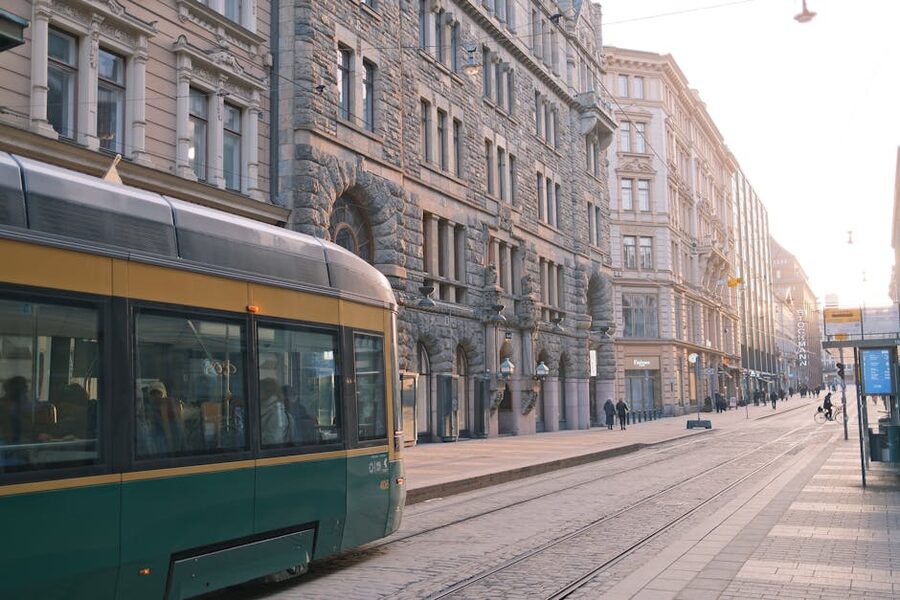 A green Helsinki tram on a historic street at sunrise