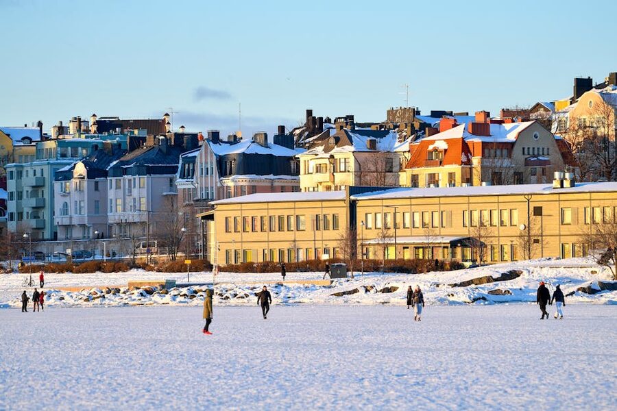 People walking on the frozen sea ice beside the colourful waterfront buildings of Helsinki