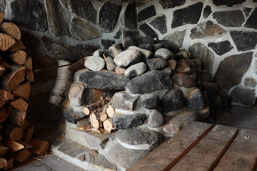 Inside a Finnish smoke sauna with the stove and dark wooden walls