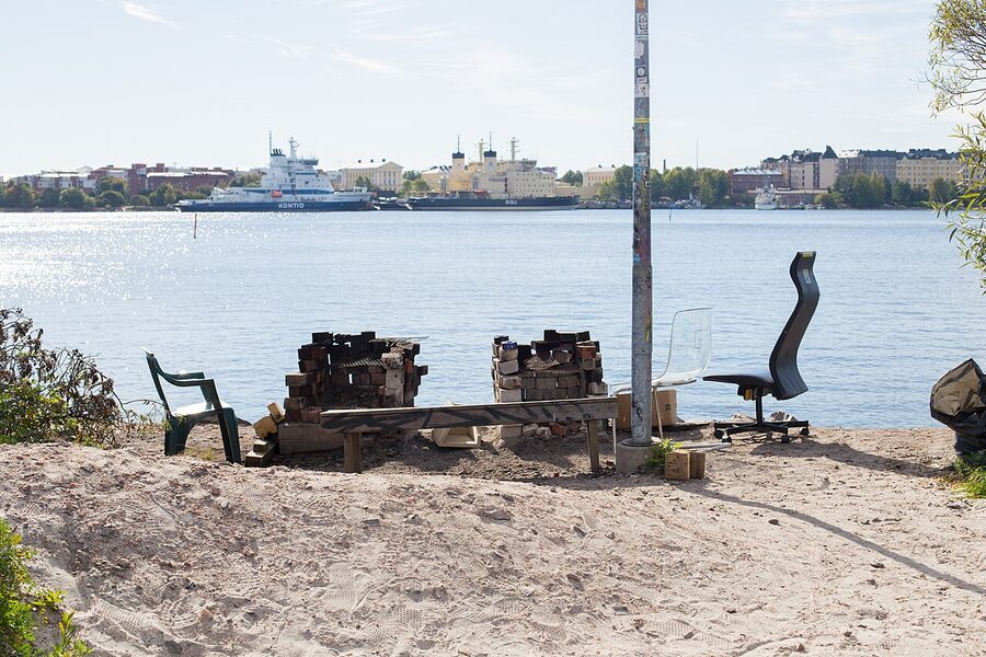 The yard at Sompasauna, with wooden benches and the Baltic Sea behind