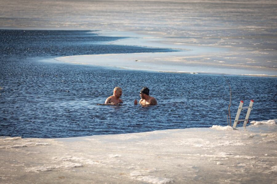A swimmer cutting through ice for a winter dip in a frozen Finnish lake