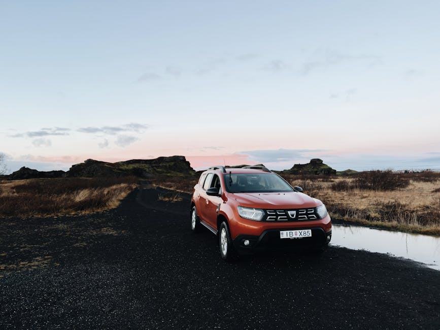 Orange SUV on a dirt road in the Icelandic countryside at sunset