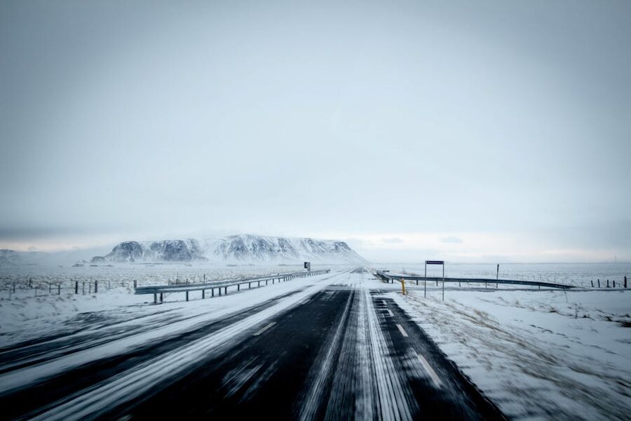 Snow-covered highway leading towards distant mountains