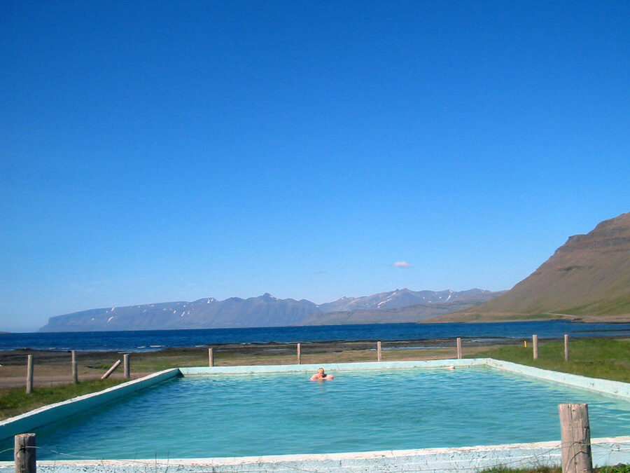 The small concrete Reykjafjarðarlaug pool by a wooden cabin in the Westfjords