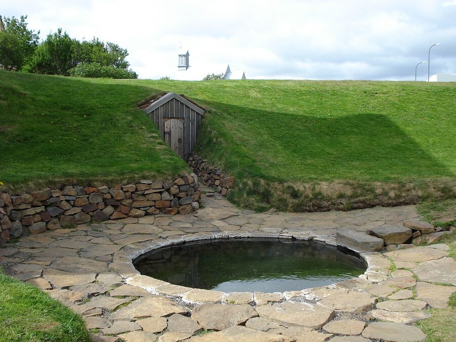 The 13th-century Snorralaug stone pool at Reykholt with a tunnel entrance