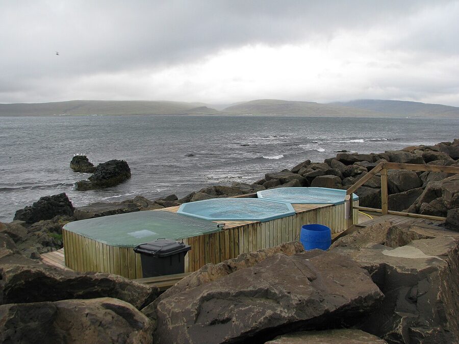 Three concrete hot pots on the shoreline at Drangsnes with the sea behind