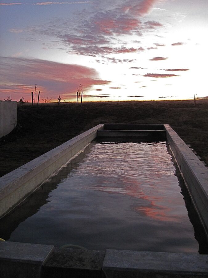 An Icelandic outdoor pool at sunset with steam rising from the water