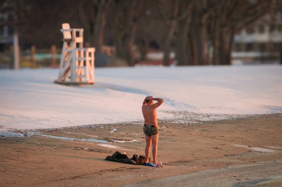 A swimmer in a swimsuit on snow-covered ground at the edge of a winter pool