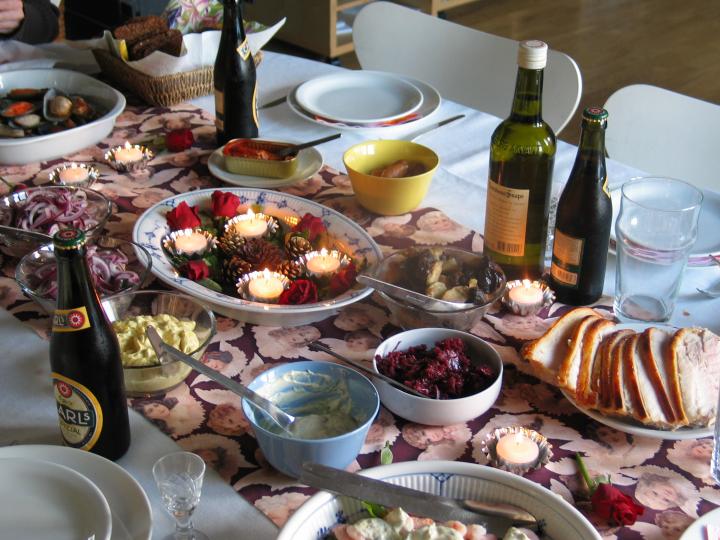 A Danish julefrokost Christmas lunch table laid with smørrebrød, herring and snaps