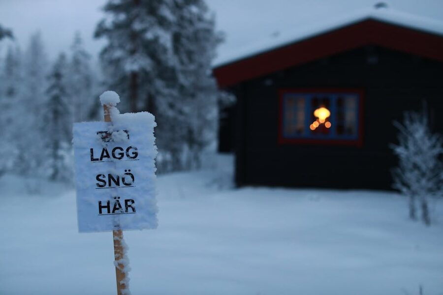 Snowy cabin with warm window light, near Kakslauttanen