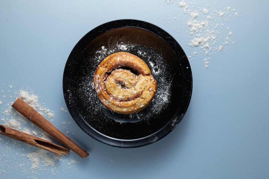 Swedish cinnamon bun (kanelbulle) sprinkled with pearl sugar on a black plate