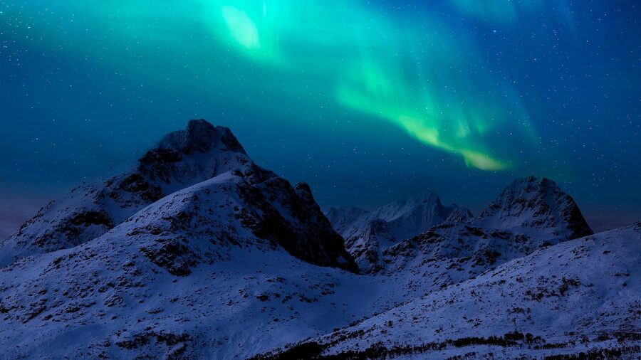 Aurora borealis above hills and a cabin