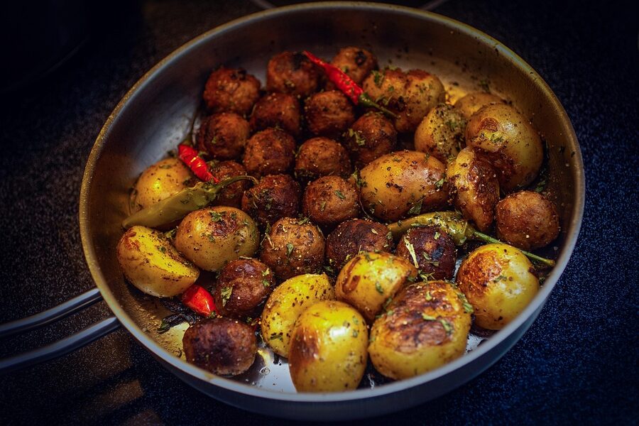 Swedish meatballs with cream sauce, lingonberry jam, and fried potatoes on a plate