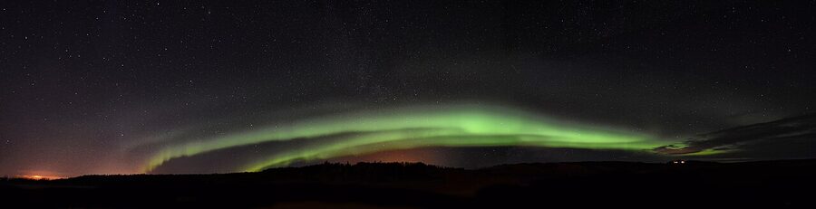 Long-exposure photograph of an auroral arch in the night sky