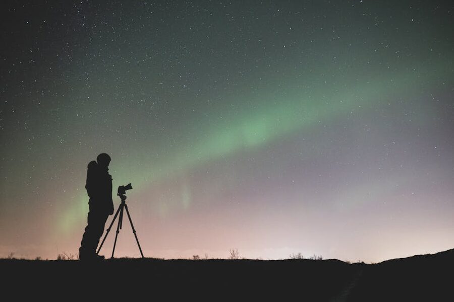 Silhouette of a photographer with a tripod capturing the Northern Lights in Iceland