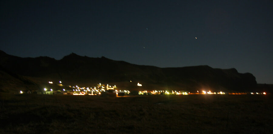 Town of Vík í Mýrdal at night, with Víkurkirkja church visible above the village
