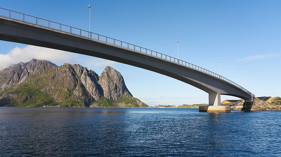 Red rorbu cabins in Reine Lofoten with sharp granite peaks behind