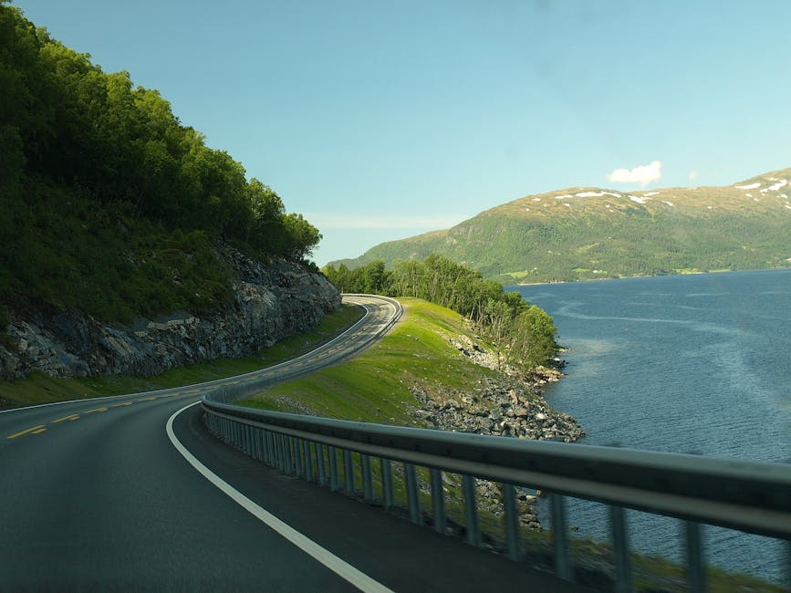 Small rental hatchback parked at a Norwegian roadside layby with fjord and mountains behind