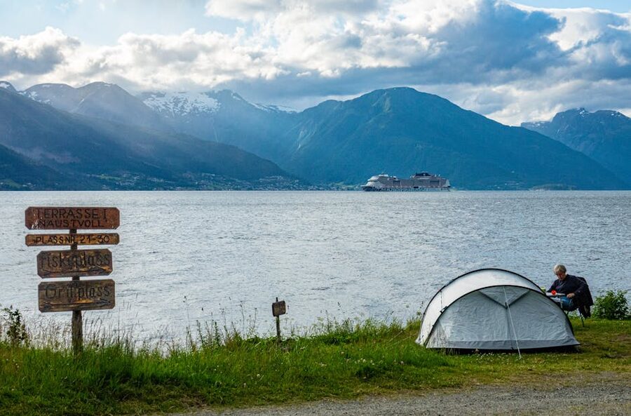 A tent pitched at a Norwegian fjord-side gravel layby at sunset