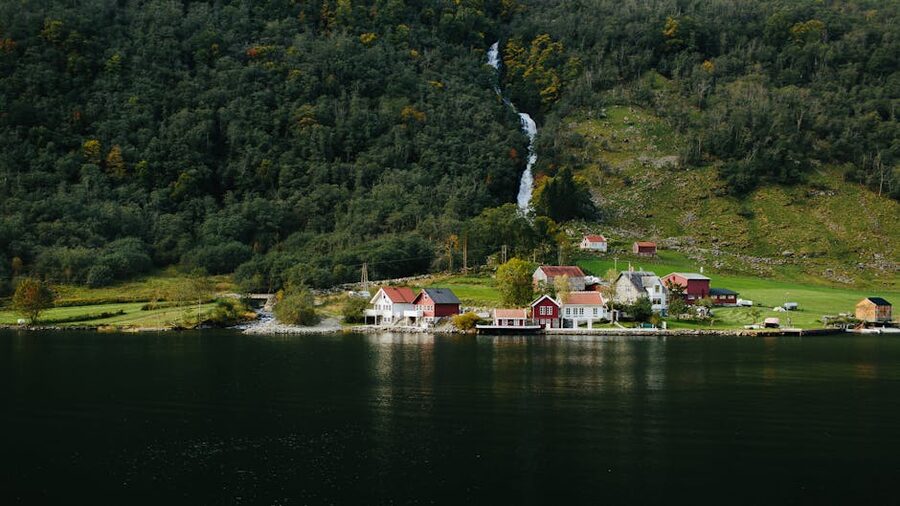 Red wooden houses by a waterfall in a Norwegian fjord village