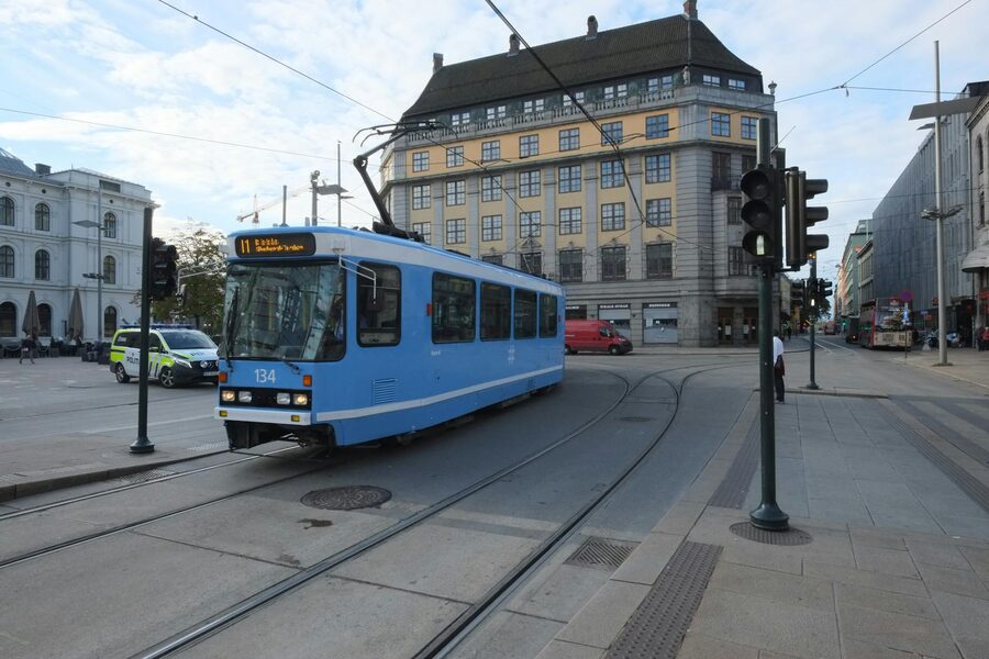 Blue tram in central Oslo with city architecture