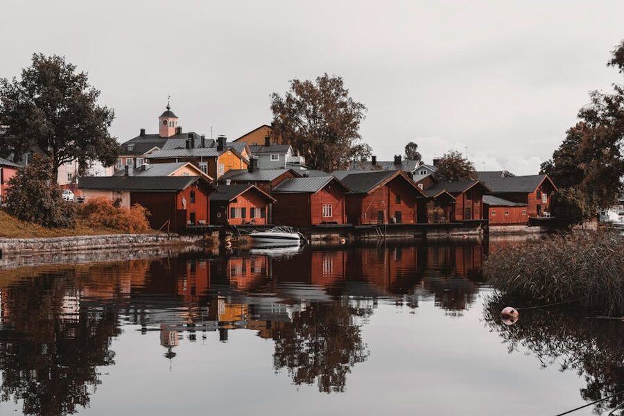 Porvoo's red warehouses reflected in the river in autumn with yellow birch trees on the bank