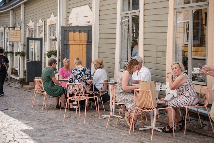 People dining outside a cafe on a Porvoo cobblestone street with wooden buildings around