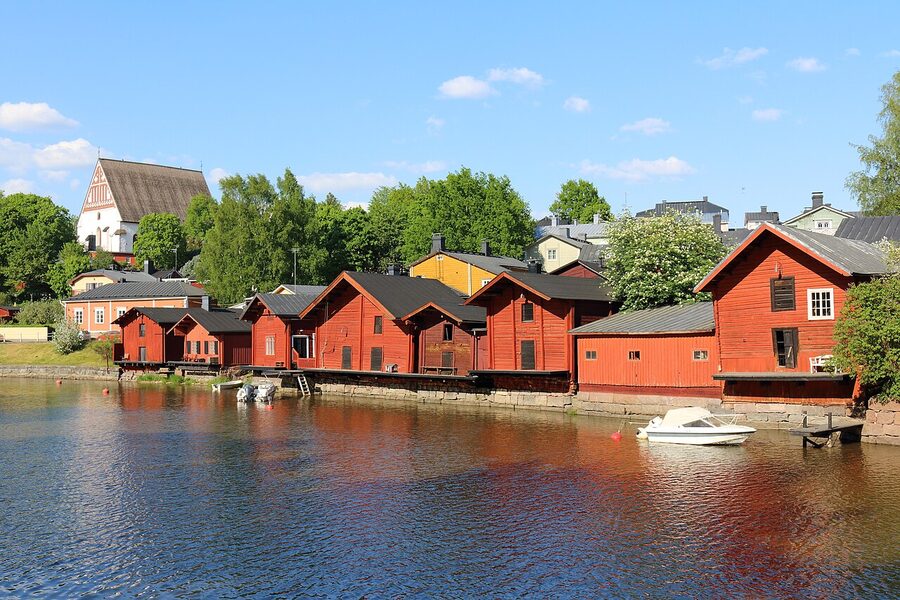 Porvoo Old Town in summer with green trees, the river, and the red warehouses in full sun