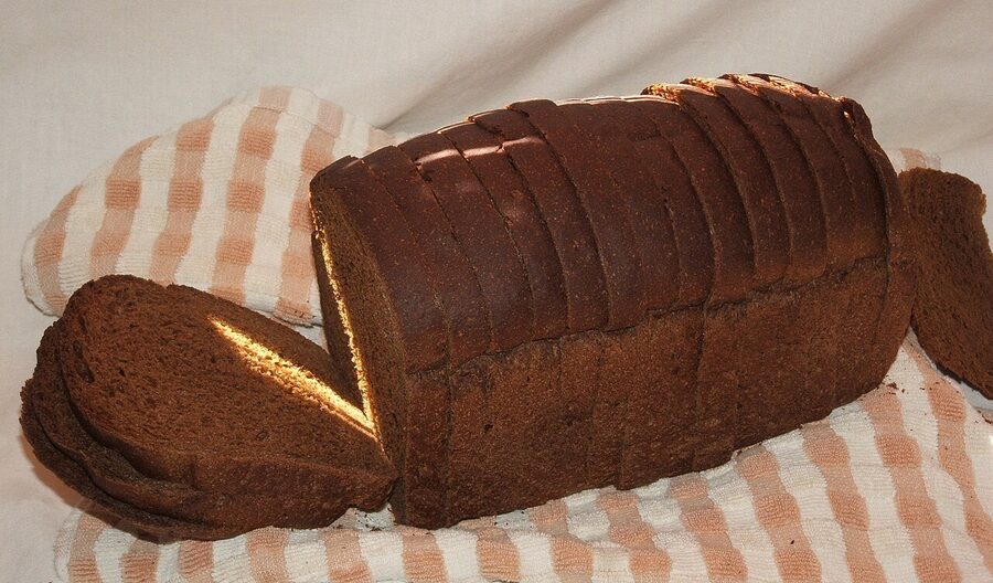 A loaf of dark Danish rye bread (rugbrød) on a wooden board