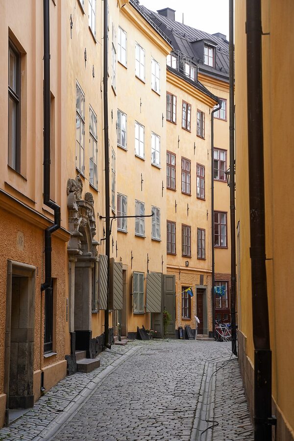 Narrow snowy alley in Gamla Stan with old yellow and ochre buildings and a single lantern