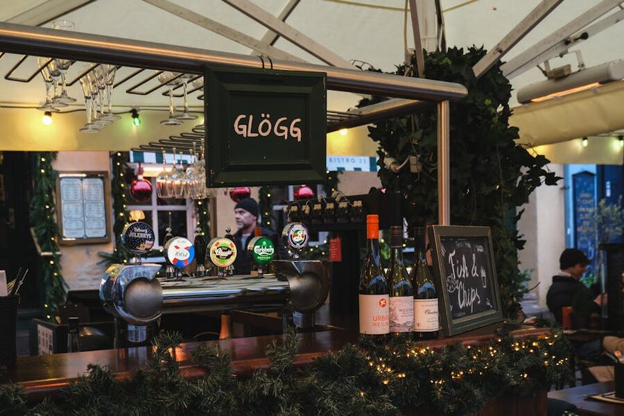 Steaming glögg in a small clear glass with raisins and almonds visible at the bottom and a sprig of cinnamon