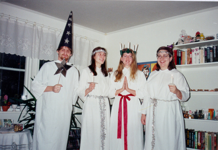Sankta Lucia procession with girls in white robes carrying candles and a leader wearing a crown of lit candles