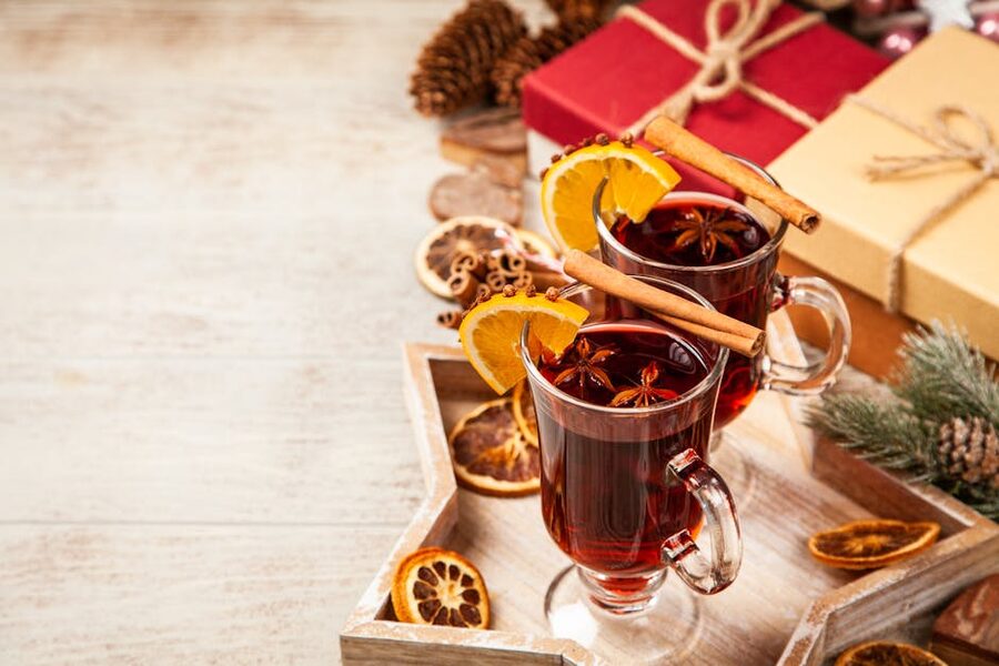 Cup of steaming glögg held in gloved hands at an outdoor Christmas market