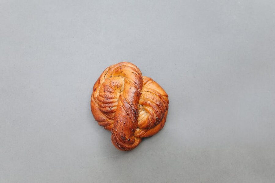 Freshly-baked saffron bun on a plate beside a steaming cup of coffee